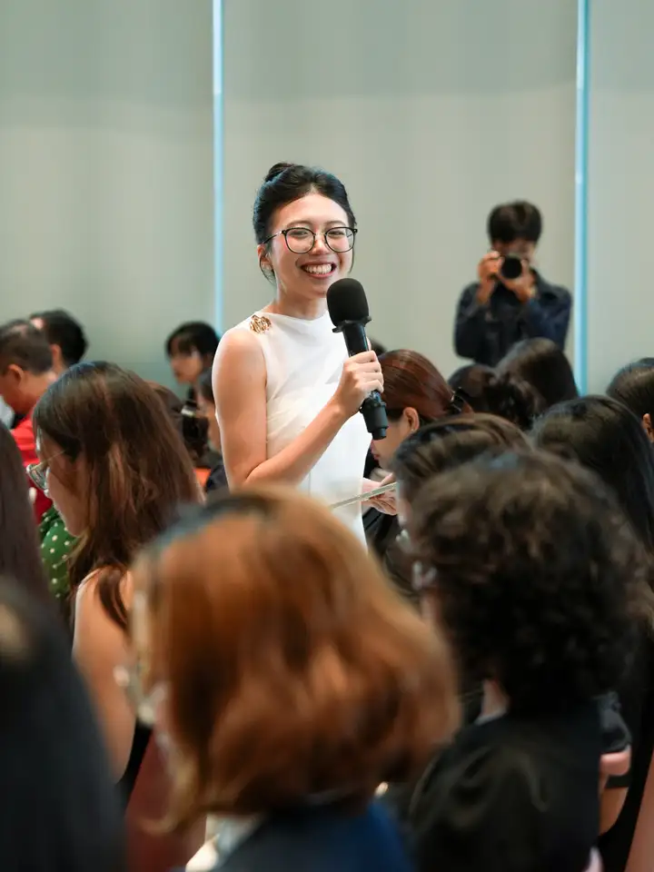 An attendee stands up in the hall, microphone in hand, to ask the speaker a question