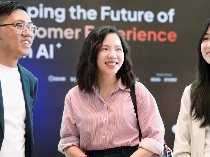 Three attendees in conversation in front of the event backdrop