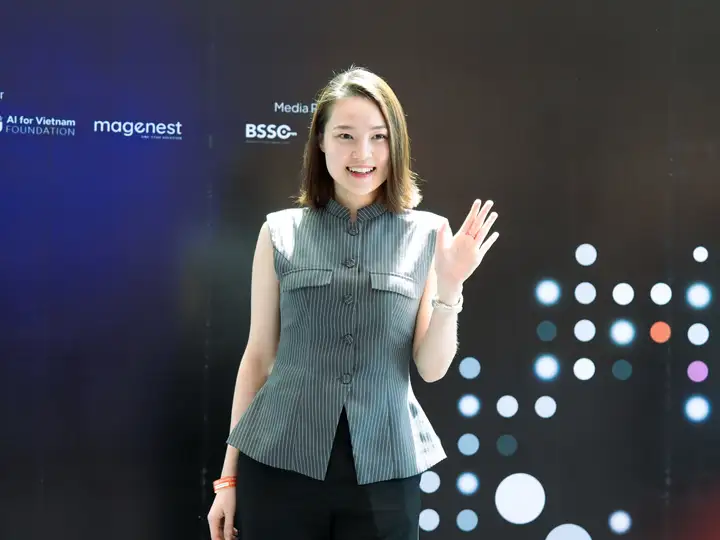 An attendee waving at the camera in front of the media wall