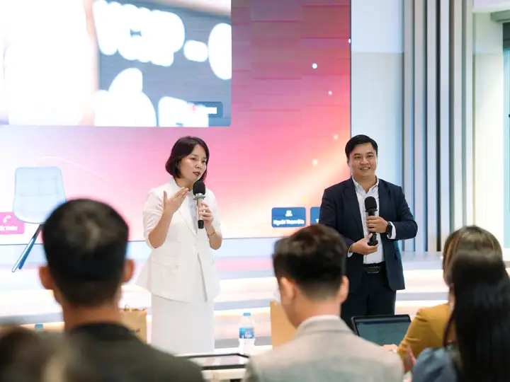 Two speakers with microphones in conversation on stage, the audience watching